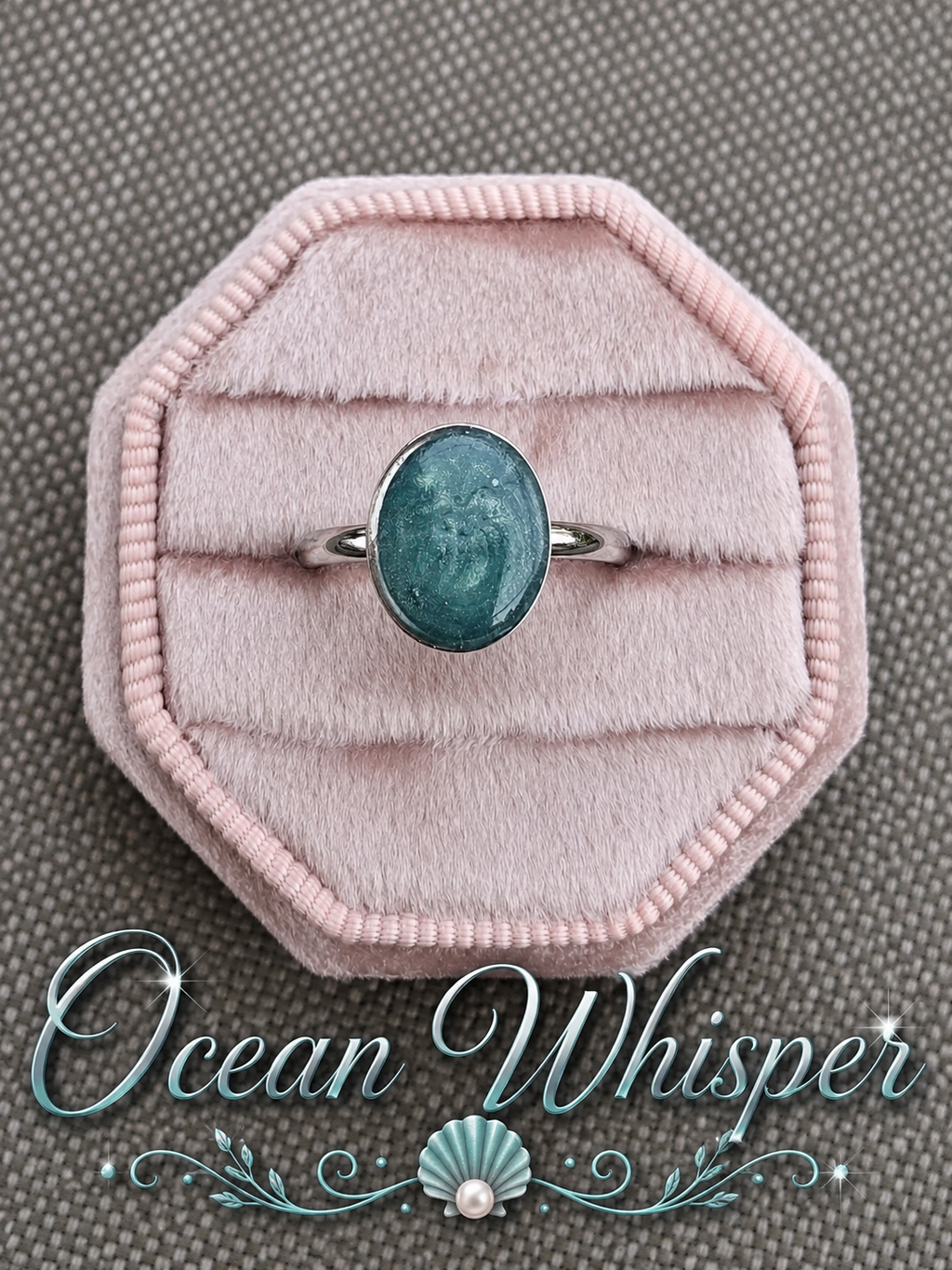 A silver ring with an oval teal-blue stone displayed on a pink velvet ring box, set against a textured gray background with the text 'Ocean Whisper' at the bottom.