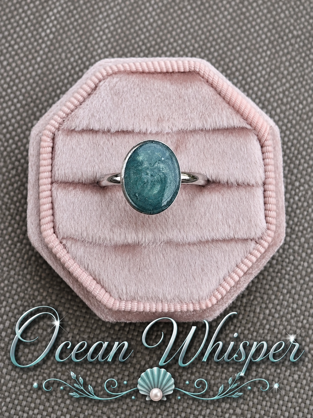 A silver ring with an oval teal-blue stone displayed on a pink velvet ring box, set against a textured gray background with the text 'Ocean Whisper' at the bottom.